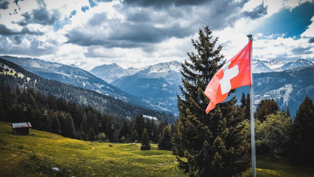 Švýcarská vlajka a výhled na krajinu
