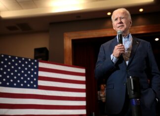Krok Joe Bidena, který pomohl kryptoměnám Americký prezident Joe Biden stojící před americkou vlajkou