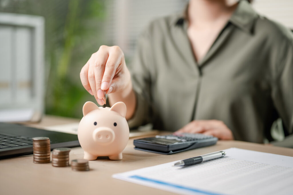A woman is putting coins into a piggy bank - ForexMag.cz příjmu, investice