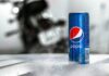 Nápojový kolos PepsiCo zvýšil čtvrtletní zisk, u růstu tržeb překonal odhady Blue Pepsi can with condensation on a textured table; a blurred motorcycle is in the background.