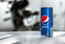 Nápojový kolos PepsiCo zvýšil čtvrtletní zisk, u růstu tržeb překonal odhady Blue Pepsi can with condensation on a textured table; a blurred motorcycle is in the background.
