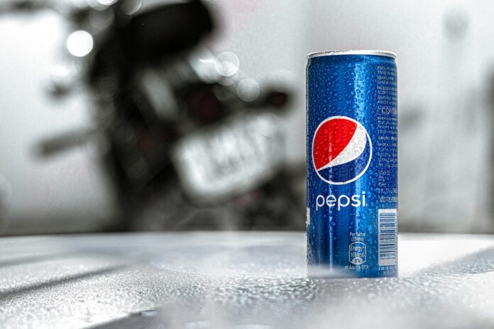 Blue Pepsi can with condensation on a textured table; a blurred motorcycle is in the background.