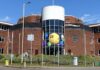 Allwyn, dříve Sazka, loni v ČR zvýšil zisk na 2,1 mld. Kč a tržby na 14,3 mld. Brick office building with a cylindrical glass atrium filled with oversized colorful lottery balls visible through the windows ch:.25 central yellow ball