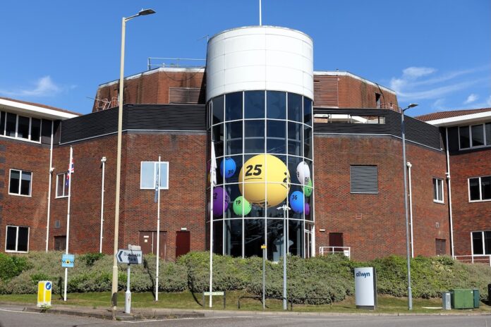 Brick office building with a cylindrical glass atrium filled with oversized colorful lottery balls visible through the windows ch:.25 central yellow ball