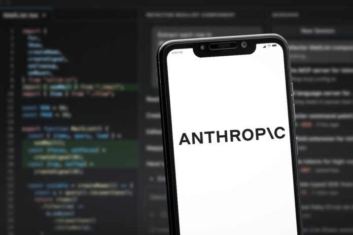 Anthropic Smartphone angled on a blurred code editor background showing the word ANTHROPIC on a white screen.