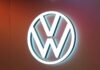 Volkswagen se dělí o výrobu baterií. Rozhodne ekonomika celého koncernu Illuminated Volkswagen logo (white VW circle) on a warm orange wall background.