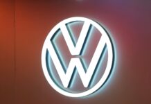 Volkswagen se dělí o výrobu baterií. Rozhodne ekonomika celého koncernu Illuminated Volkswagen logo (white VW circle) on a warm orange wall background.