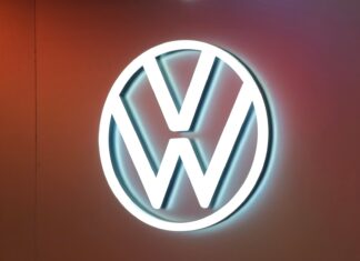 Volkswagen se dělí o výrobu baterií. Rozhodne ekonomika celého koncernu Illuminated Volkswagen logo (white VW circle) on a warm orange wall background.