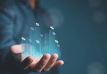 Společnost TD SYNNEX výrazně překonala očekávání: tržby vyskočily o 38 %, akcie však po zveřejnění výsledků klesly Hand holding a glowing holographic bar chart with percent signs rising from the palm