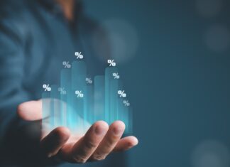 Společnost TD SYNNEX výrazně překonala očekávání: tržby vyskočily o 38 %, akcie však po zveřejnění výsledků klesly Hand holding a glowing holographic bar chart with percent signs rising from the palm